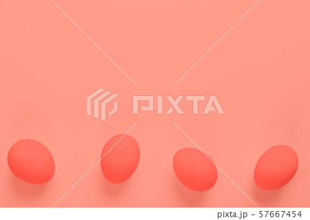 Four Easter eggs lying on bottom of trendy coral background. Easter trendy design. Top view, bright trendy color, copy space. 57667454