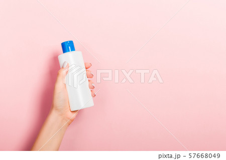 Female hand holding cream bottle of lotion 57668049