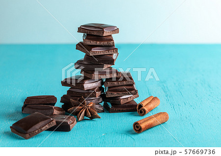 Vertical stack of squared slices of chocolate on painted in turquoise color wooden background. Selective focus, copy space. 57669736