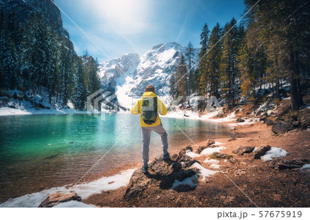 Man with backpack on the stone near lake with Man with backpack on the stone near lake with 57675919