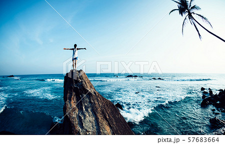 Successful woman outstretched arms on seaside rock Successful woman outstretched arms on seaside rock 57683664
