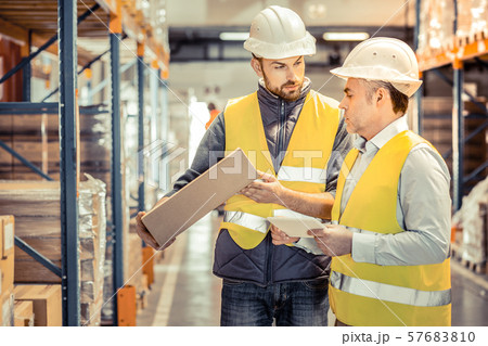 Serious young manager consulting his competent colleague Serious young manager consulting his competent colleague 57683810