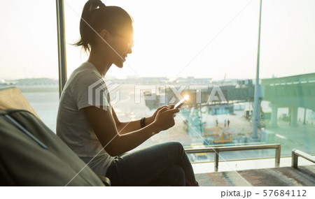 Woman passenger using mobile phone in airport Woman passenger using mobile phone in airport 57684112