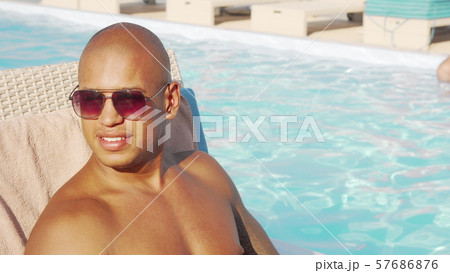 Relaxed handsome African man sipping his cocktail by the swimming pool 57686876