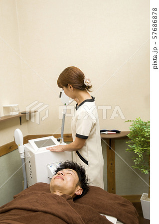 業務用脱毛機の設定をするエステティシャン 57686878