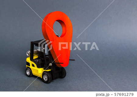 Yellow fork lift carries a red location pointer. Transportation services and logistics management in production warehouse. Destination cargo and parcels, tracking. Technological processes at factory 57691279