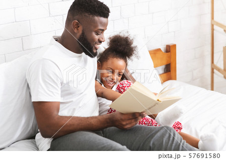 Loving african american dad reading fairy tales to his little daughter Loving african american dad reading fairy tales to his little daughter 57691580