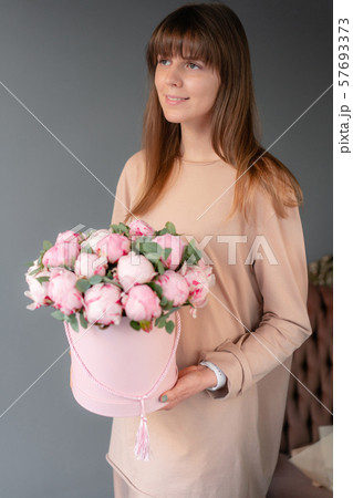 Pink peonies in pink round box. Beautiful peony flower in womans hands for catalog or online store 57693373
