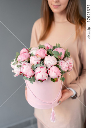 Pink peonies in pink round box. Beautiful peony flower in womans hands for catalog or online store 57693375