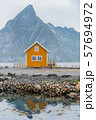 A yellow fishing cabin in Sakrisoy, a small fishing village in Moskenes Municipality on Lofoten islands in Nordland county, Norway with a mountain in background 57694972