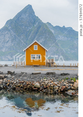 A yellow fishing cabin in Sakrisoy, a small fishing village in Moskenes Municipality on Lofoten islands in Nordland county, Norway with a mountain in background 57694972