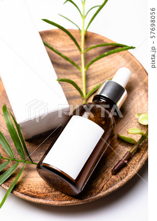 Brown glass cosmetic bottle mock-up with blank white label and green leaves, serum packaging Brown glass cosmetic bottle mock-up with blank white label and green leaves, serum packaging 57698056