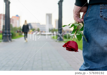 red rose flower in the hand of the guy on the background of the girl 57699192