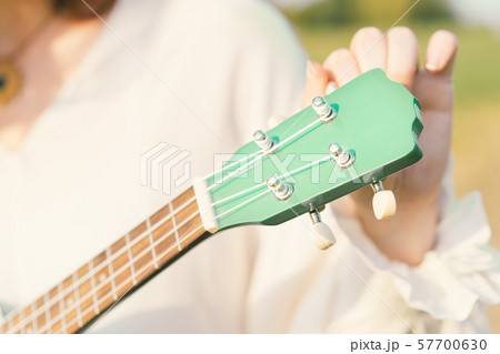 Woman tuning ukulele strings. The fretboard of the musical instrument 57700630