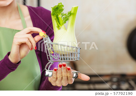 Woman holding shopping cart with fennel inside Woman holding shopping cart with fennel inside 57702190