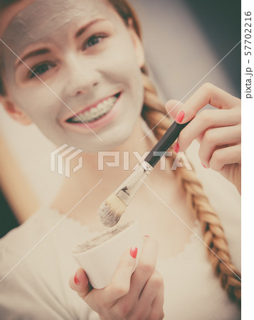Woman applying with brush clay mud mask to her Woman applying with brush clay mud mask to her 57702216