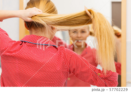 Woman combing her long hair in bathroom Woman combing her long hair in bathroom 57702229