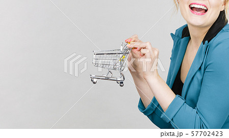 Happy woman holding small tiny shopping cart 57702423