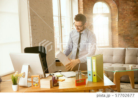 A young businessman moving in office, getting new work place A young businessman moving in office, getting new work place 57702677