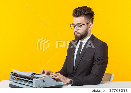 Arab businessman or manager in formal suit typing text on a typewriter on a yellow background 57703058