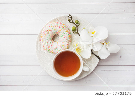 Cup of tea and donuts, white orchid on white table with copy space. Flat lay, top view. 57703179