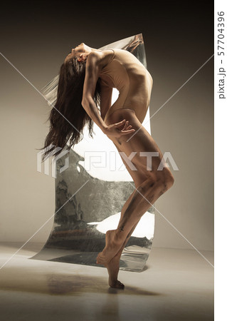 Young and stylish modern ballet dancer on brown background Young and stylish modern ballet dancer on brown background 57704396