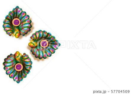 Happy Diwali - Clay Diya lamps lit during Dipavali, Hindu festival of lights celebration. Colorful traditional oil lamp diya on white background. Copy space for text. 57704509