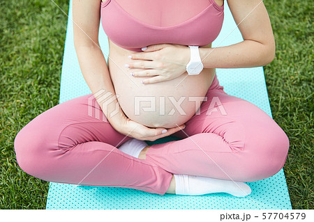 Pregnant woman sitting on exercise mat 57704579