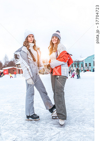 Two women girlfriends posing winter warm clothes, sweaters and hats, smiling happy, relaxing on Two women girlfriends posing winter warm clothes, sweaters and hats, smiling happy, relaxing on 57704723