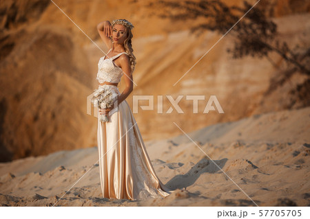 Beautiful bride is wearing fashion flying dress and wreath in the great desert in Dubai. 57705705