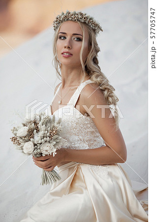 Portrait of beautiful bride is wearing fashion flying dress and wreath in the great desert in Dubai. 57705747