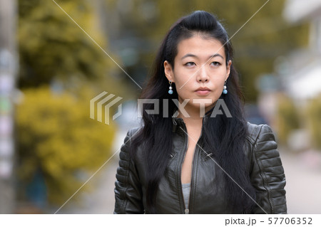 Face of beautiful Asian rebellious woman thinking outdoors 57706352