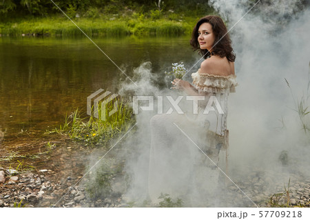 One bride is sitting on the banks of a foggy 57709218