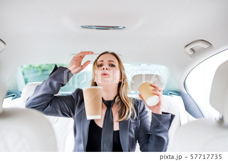 Young frustrated woman with empty paper glasses sitting in car. 57717735