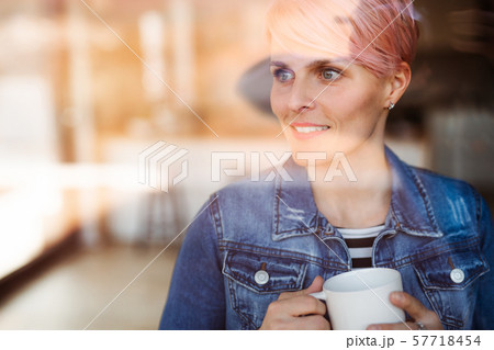 A close-up portrait of young attractive woman standing by window at home. 57718454