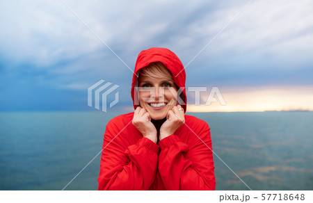 Young woman standing outdoors on beach at dusk., looking at camera. 57718648