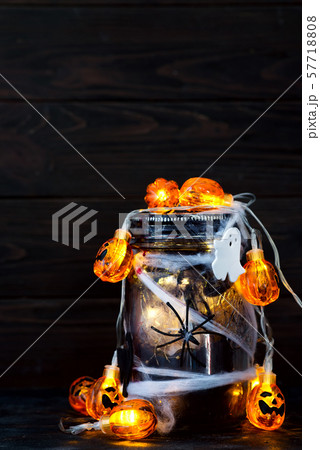 Jar filled with orange string lights in spooky room full of black webs. Jar filled with orange string lights in spooky room full of black webs. 57718808