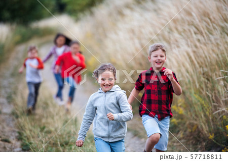Group of school children running on field trip in nature. 57718811
