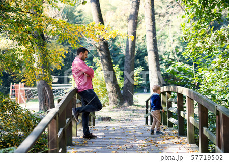 Father with small son on a walk in autumn park, standing on bridge. Father with small son on a walk in autumn park, standing on bridge. 57719502