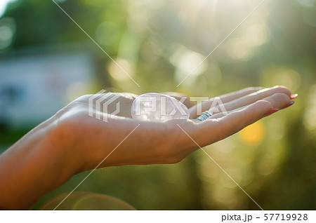 Female hand with transparent amethyst quartz yoni egg for vumfit, imbuilding or meditation. Shining 57719928