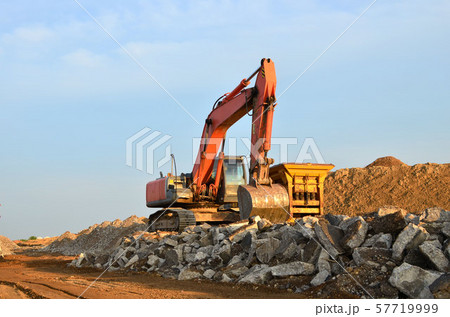 Heavy tracked excavator load stone, old asphalt or concrete waste into a mobile jaw crusher machine. Heavy tracked excavator load stone, old asphalt or concrete waste into a mobile jaw crusher machine. 57719999