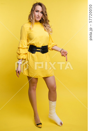 Woman with broken bone on yellow background. 57720050