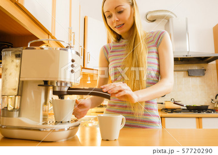 Woman in kitchen making coffee from machine Woman in kitchen making coffee from machine 57720290
