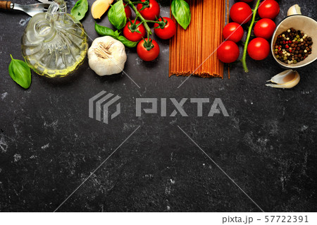 Top view on dry pasta and fresh cherry tomatoes on dark black background 57722391