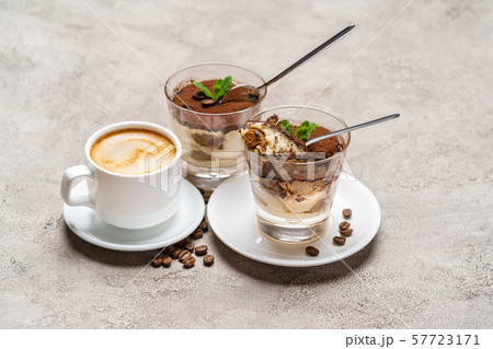 Portion of Classic tiramisu dessert in a glass and cup of coffee on concrete background 57723171