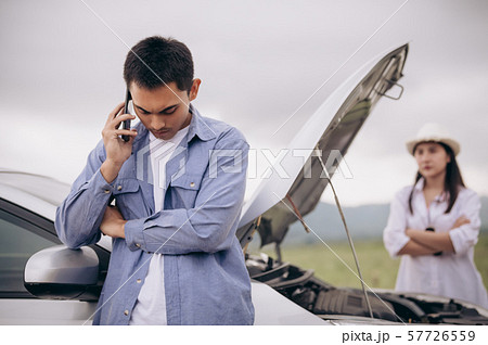 Asian man calling car maintenance service with his Asian man calling car maintenance service with his 57726559