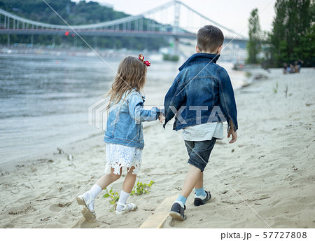 Two children walking along the beach 57727808
