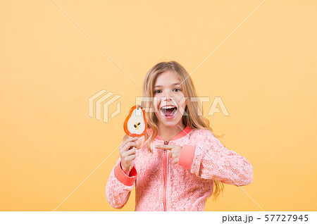 Girl point finger at lollipop on orange background 57727945