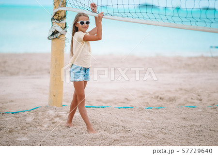 Little adorable girl playing voleyball on beach with ball. 57729640