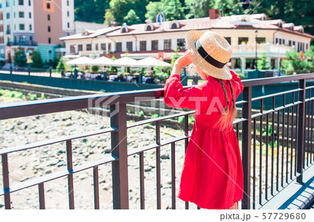 Little girl at hat on the embankment of a mountain river in a European city. 57729680